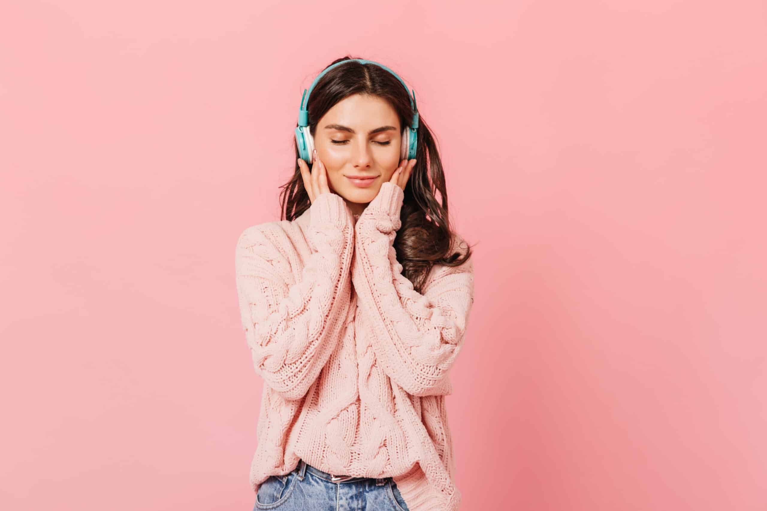 Mujer joven con los ojos cerrados y auriculares puestos, experimentando una fuerte conexión emocional gracias al poder del audio branding y el marketing auditivo.