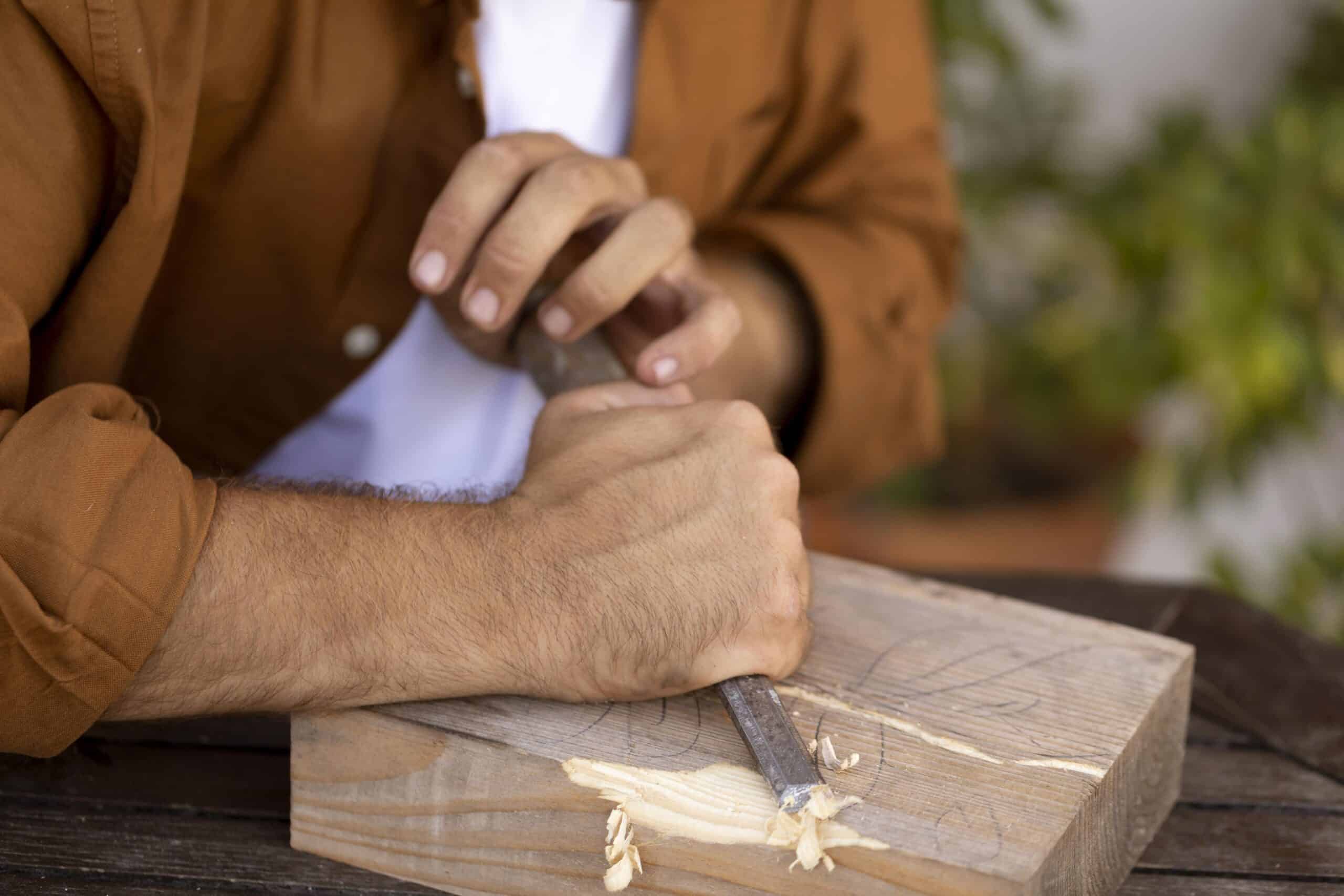 Manos expertas de un artesano tallando con precisión un bloque de madera, una metáfora de cómo se debe construir confianza en una marca personal.