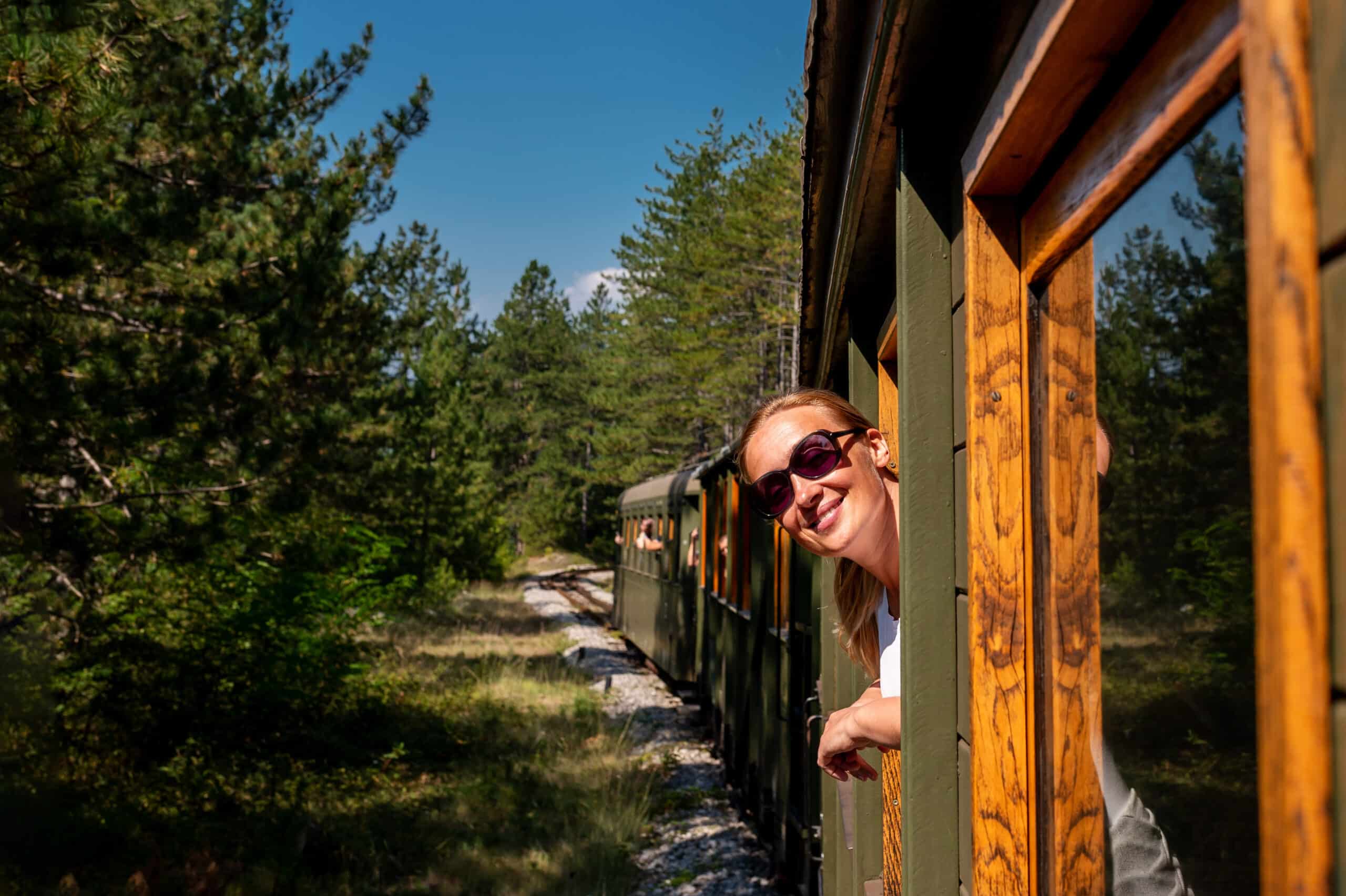 Una persona mirando por la ventana de un tren que atraviesa un paisaje idílico, representando el customer journey del slow branding: un viaje consciente que valora la experiencia y la conexión por encima de la velocidad.