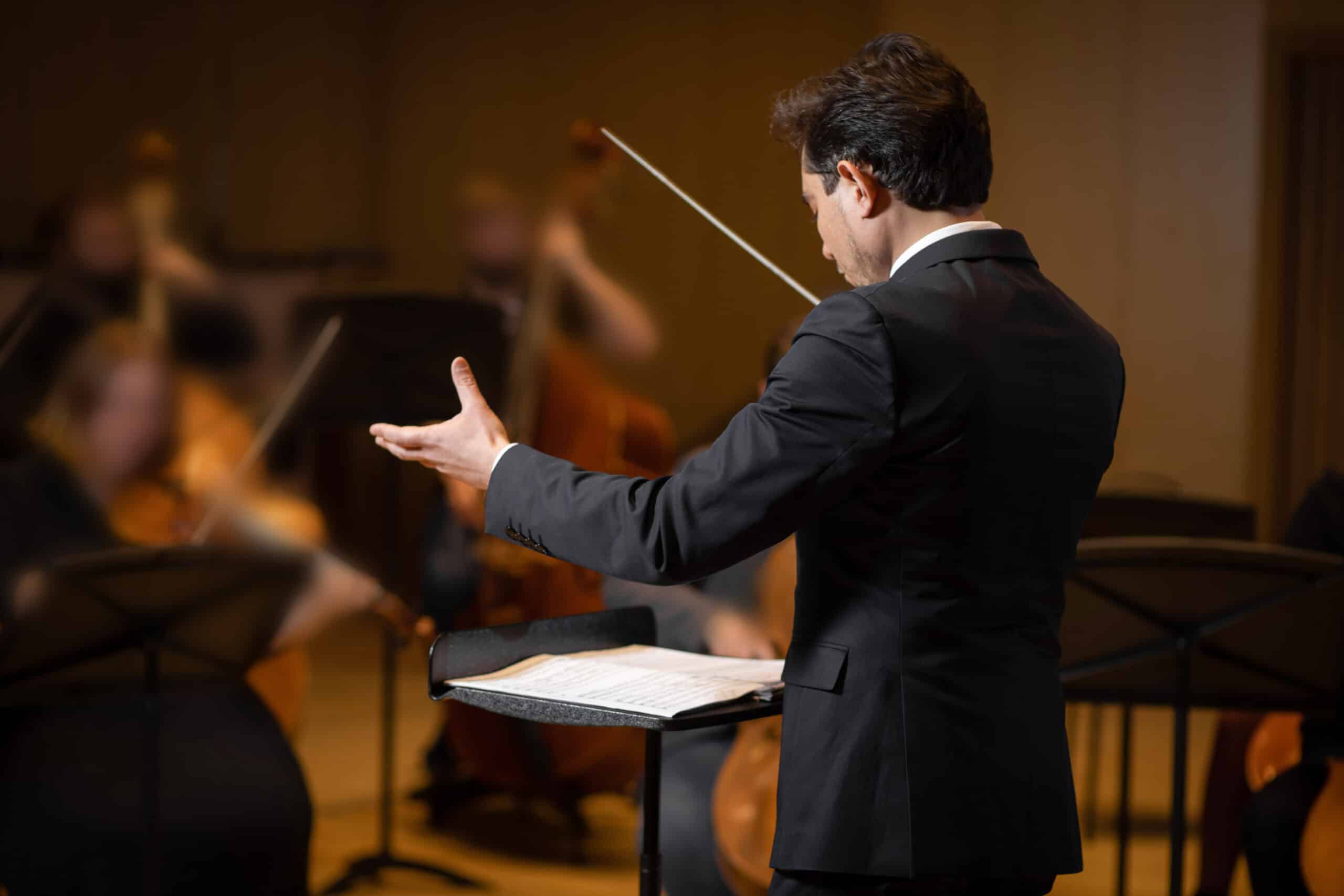 Metáfora visual de un director de orquesta dirigiendo a marcas líderes como ejemplos de un tono de voz de marca bien definido y exitoso.