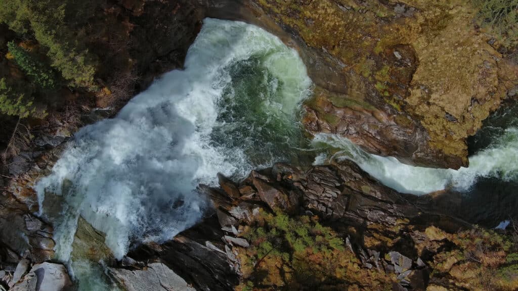 Una vista aérea de un río caudaloso que fluye y se adapta alrededor de rocas, ilustrando el concepto de qué es una marca líquida.